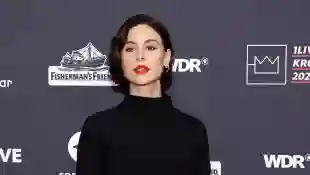 Lena Meyer-Landrut posiert mit rotem Lippenstift und in einem schwarzen hochgeschlossenen Kleid bei einer Veranstaltung im Dezember 2022