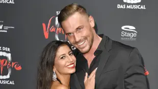 Eva Benetatou und Chris Broy umarmen sich fest auf einem roten Teppich