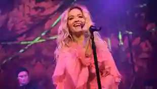 Rita Ora singt in einem pinken Kleid auf der Bühne und lacht im Januar 2018