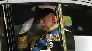 König Charles III. sitzt in einem Auto mit heruntergelassener Scheibe