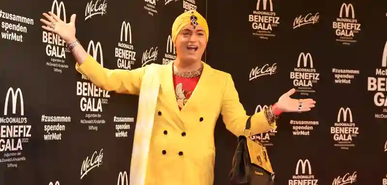 Julian F. M. Stoeckel in einem gelben Blazer und mit gelbem Kopftuch bei der McDonald's Benefiz Gala 2022