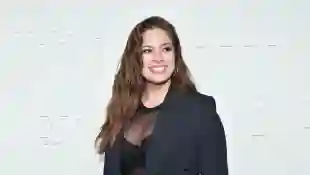 Ashley Graham posiert in einem transparentem Top mit Blazer lächeln auf dem Roten Teppich