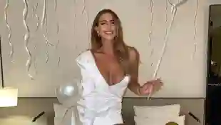 Jessica Paszka vor ihrer Hochzeit in einem weißen Kleid mit weißen Overknees auf einem Bett in Deutschland 2021