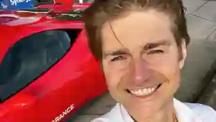 Jeremy Fragrance posiert mit seinem roten Ferrari