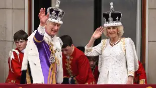 König Charles und Königin Camilla nach ihrer Krönung winkend auf dem Balkon des Palastes