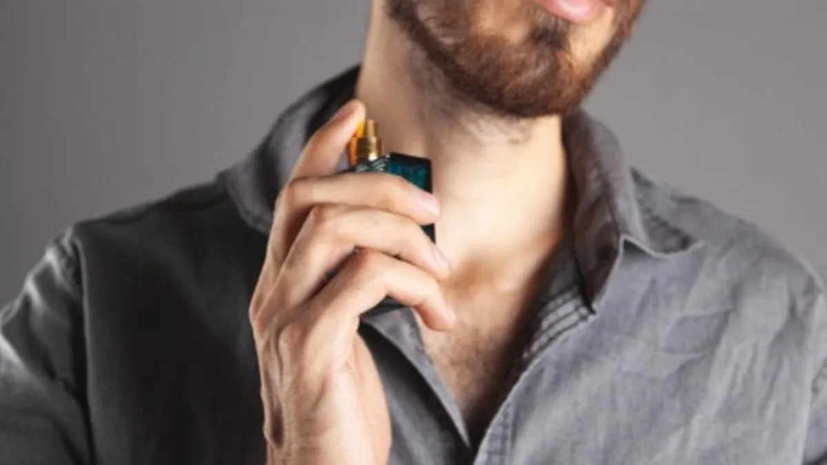 Mann sprüh sich mit Parfum ein