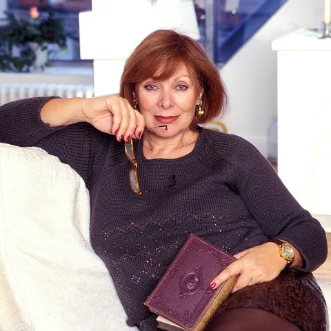 Heide Keller zuhause auf dem Sofa sitzend mit Buch