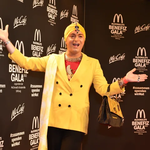 Julian F. M. Stoeckel in einem gelben Blazer und mit gelbem Kopftuch bei der McDonald's Benefiz Gala 2022