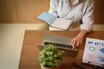 Cropped shot of female manager holding her personal daily planner and using laptop at desk. Model Re