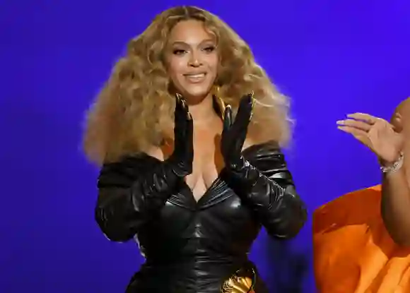 Beyoncé klatscht in die Hände, an denen sie schwarze Handschuhe trägt