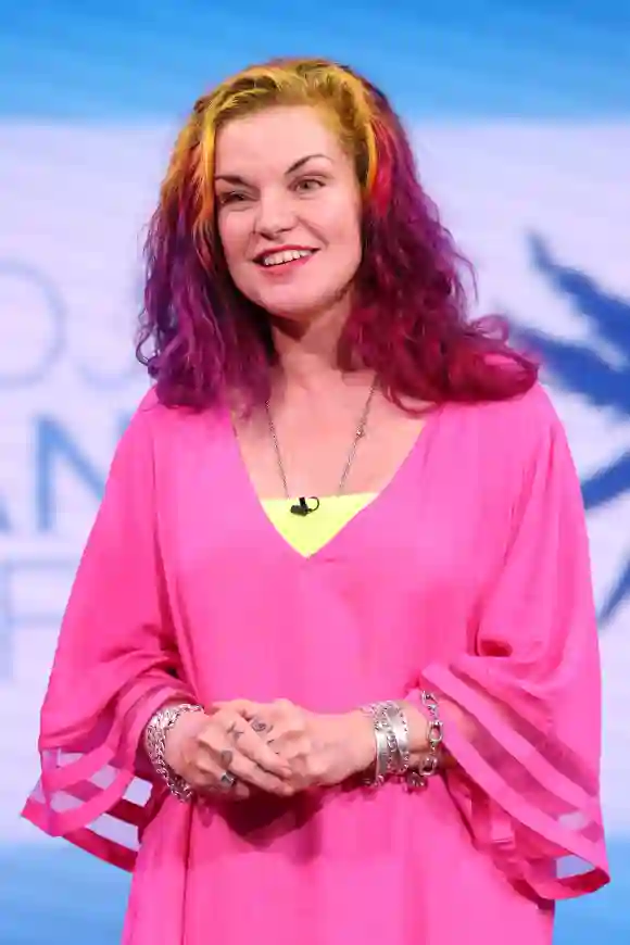 Pauley Perrette  in einem pinken Kleid und mit bunten Haaren