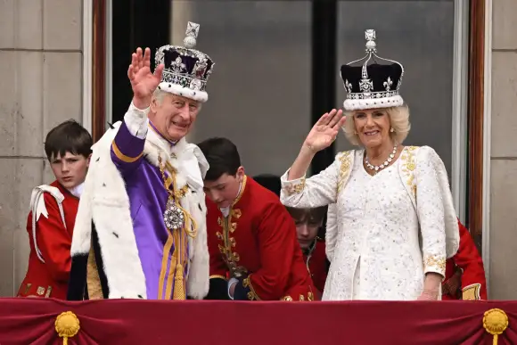 König Charles und Königin Camilla nach ihrer Krönung winkend auf dem Balkon des Palastes