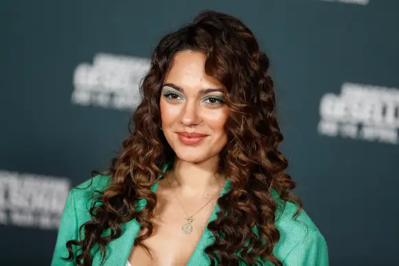 Nilam Farooq in einem grünen Hosenanzug und mit grünem Augen-Make-up auf dem roten Teppich 2022